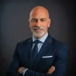 Confident gray-bearded agent in navy suit stands poised—expert in Ulcinj, Montenegro real estate for immobilien.ekosphere.me by Ekosphere.