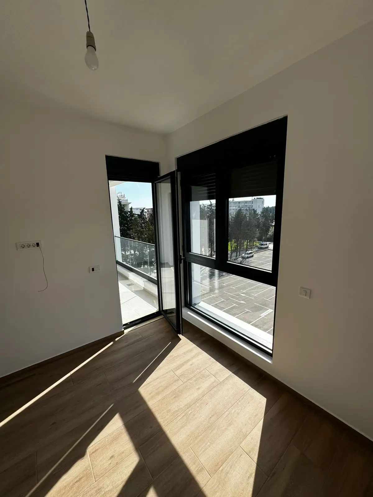 Bright, modern room in Ulcinj with wood floors and balcony access&mdash;invest in Montenegro real estate via immobilien.ekosphere.me by ekosphere doo.