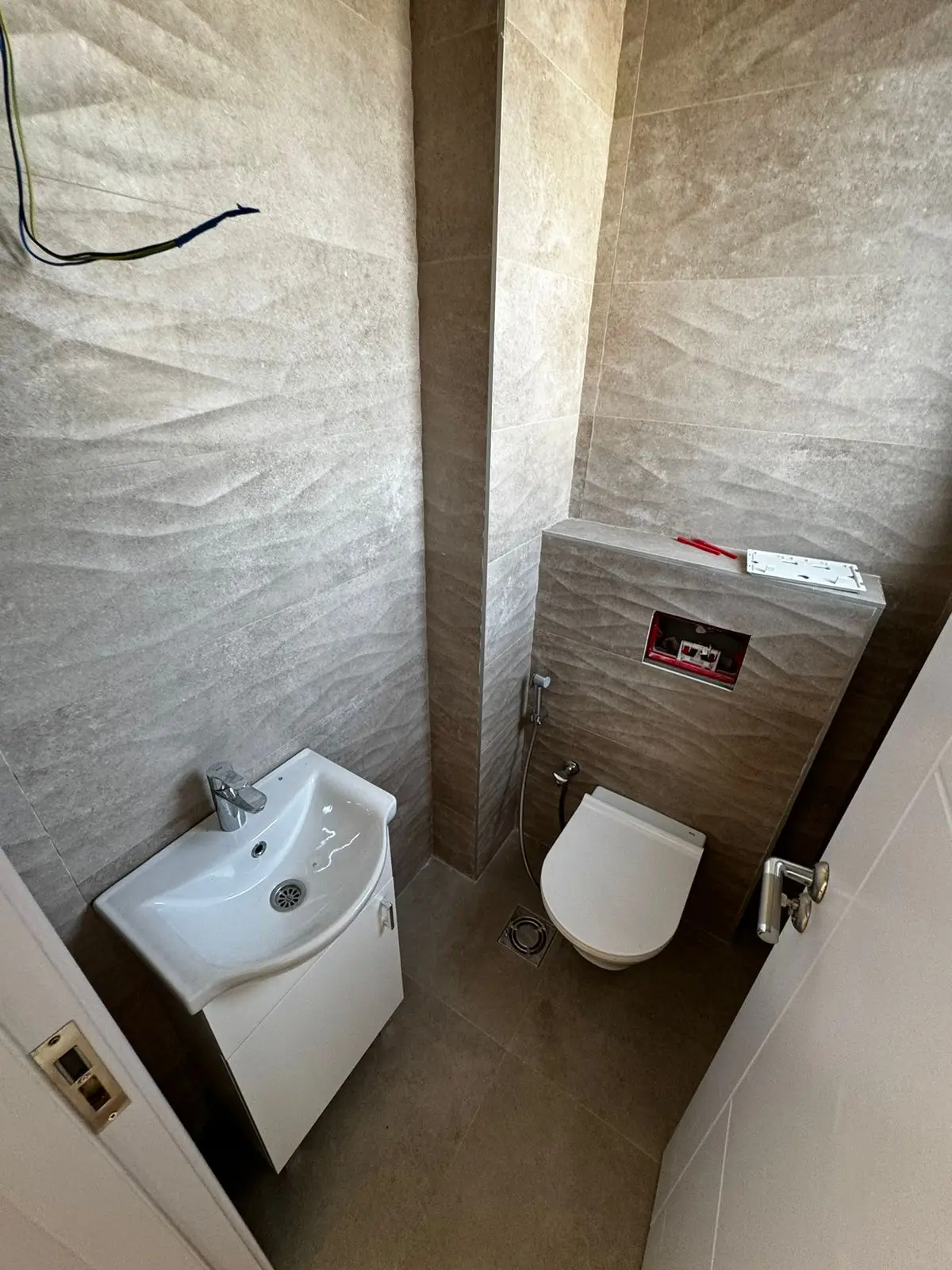 Stylish modern bathroom in Ulcinj, Montenegro&mdash;beige tiles, wall toilet, sink cabinet; ideal investment via immobilien.ekosphere.me (EkoSphere).