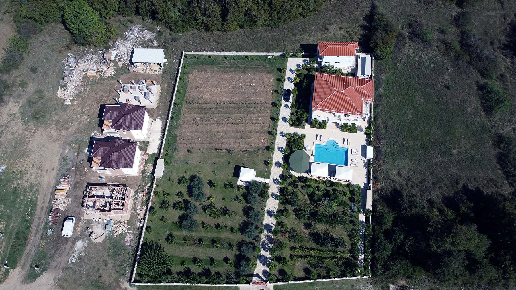 Prime Ulcinj real estate: garden, pool, red-roofed villa, Ekosphere homes under construction amid lush greenery. immobilien.ekosphere.me.