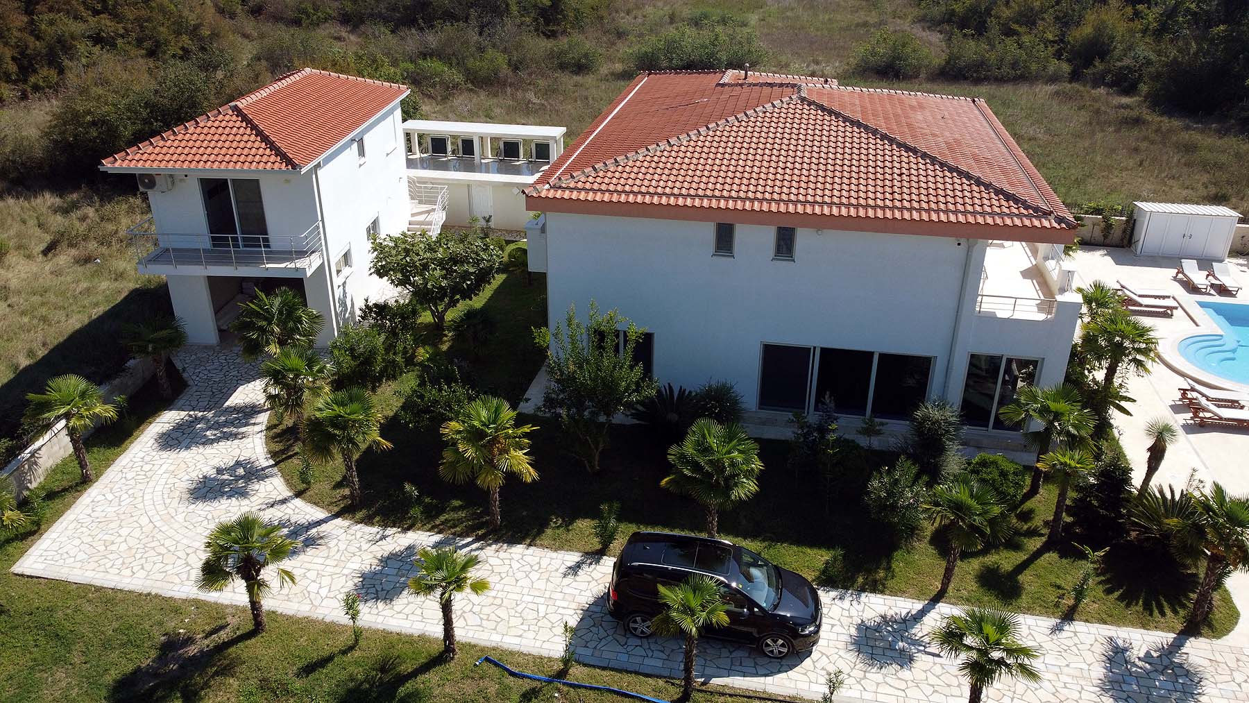 Exclusive aerial view of a luxury white villa with pool, palm trees, and lush Ekosphere landscaping in Ulcinj&mdash;listed on immobilien.ekosphere.me.