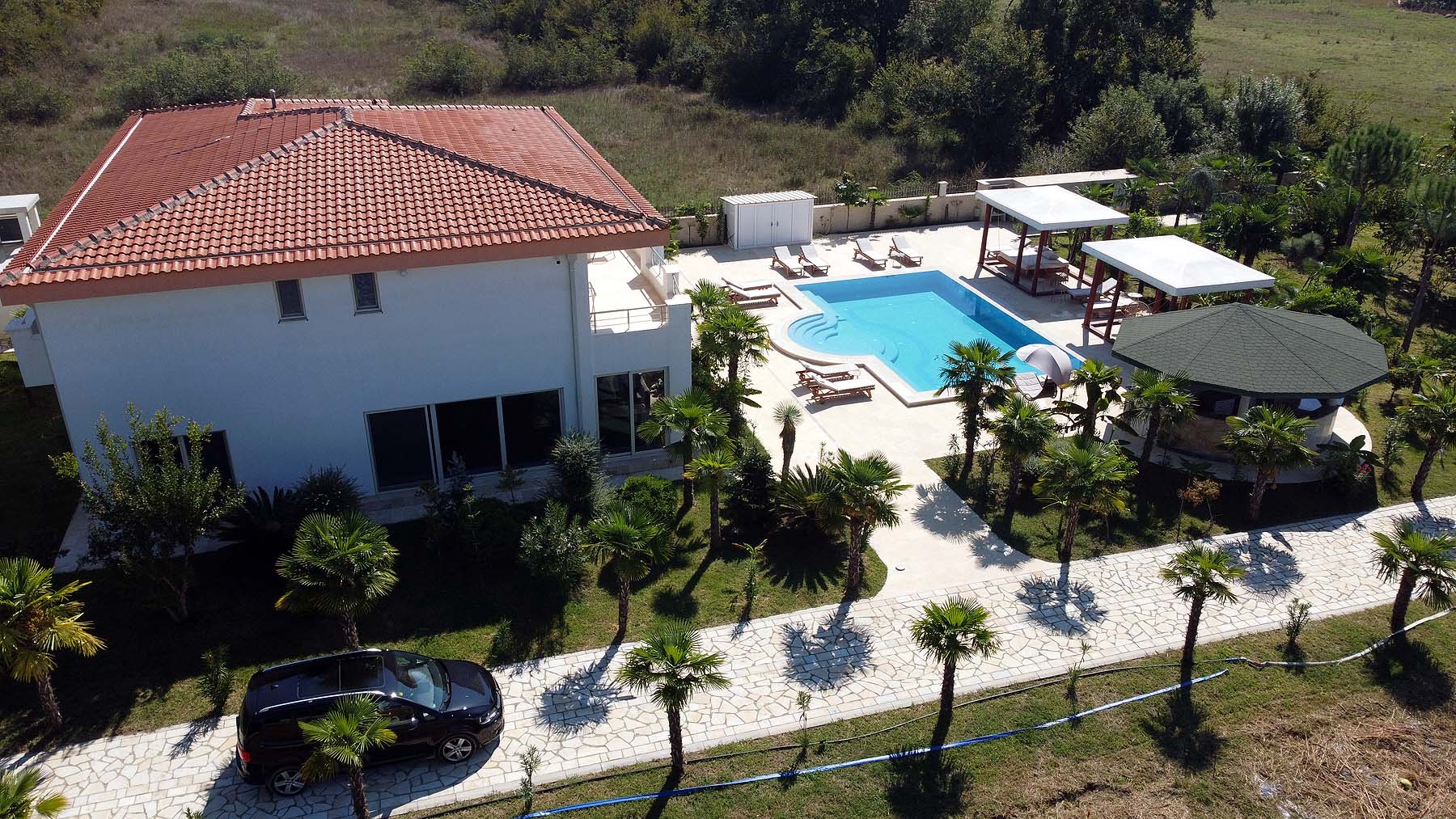 Aerial view of luxury Ulcinj villa for sale: red-tiled roof, pool, gazebo, palm-lined drive&mdash;exclusive at immobilien.ekosphere.me by ekosphere doo.