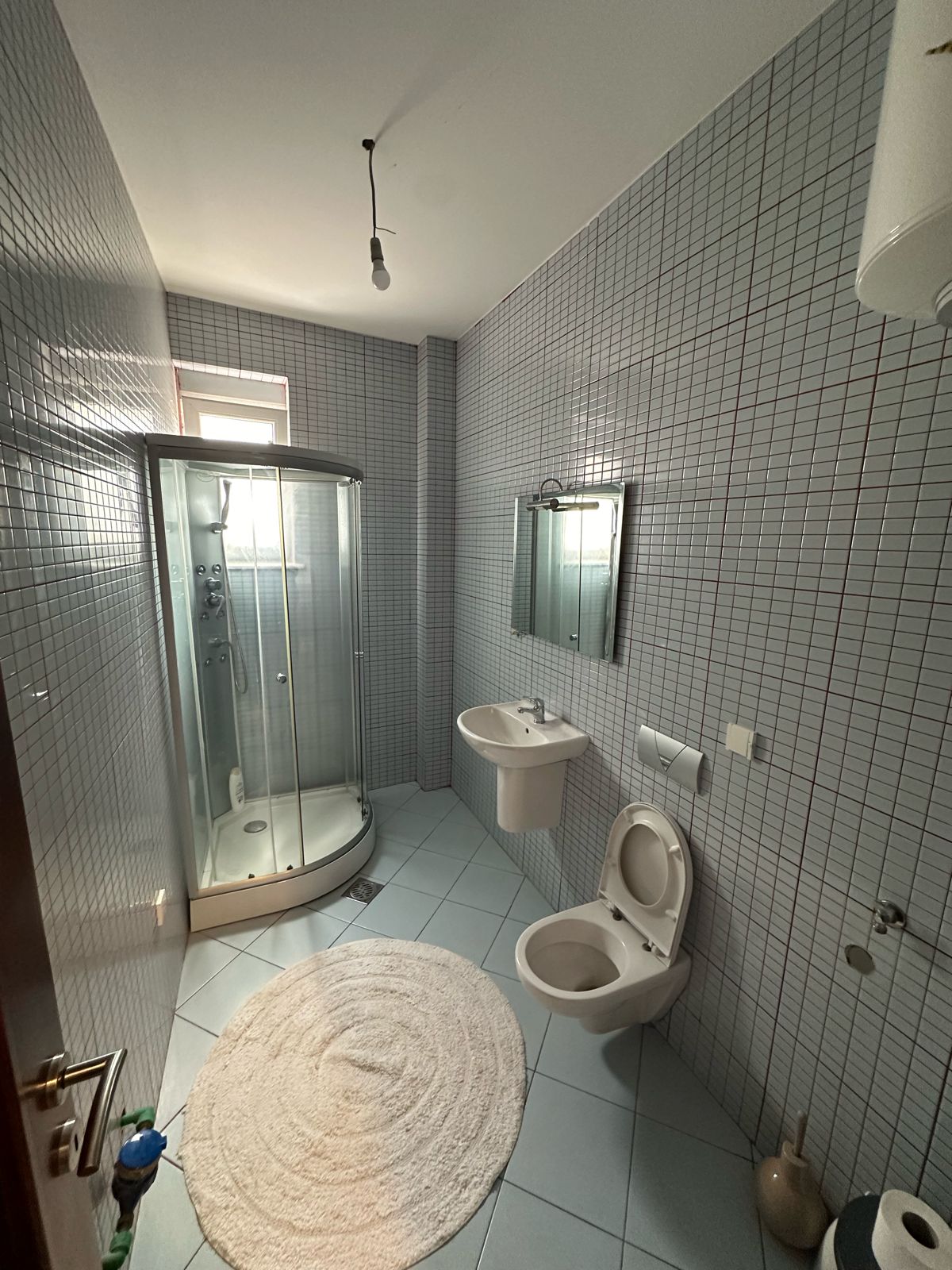 Modern bathroom at Ekosphere in Ulcinj: gray tiles, glass shower, wall sink, premium fixtures. Exclusive on immobilien.ekosphere.me.