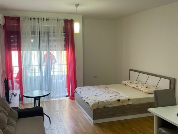 Bright Ulcinj studio: modern bed, beige sofa, dining area, wood floors, large windows. Invest via immobilien.ekosphere.me by Ekosphere doo.