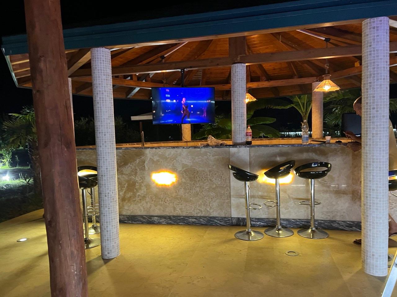 Stunning outdoor bar with tiled counter and TV, under elegant beams&mdash;exclusive Ulcinj real estate at immobilien.ekosphere.me by Ekosphere.
