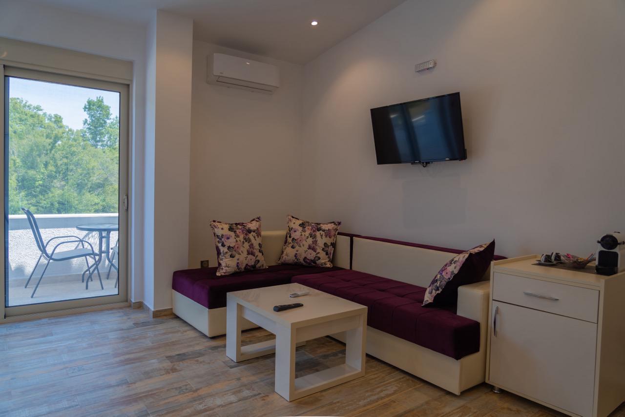 Experience luxury living in Ulcinj Montenegro&mdash;modern lounge, elegant maroon sofa, patio access. Exclusive via immobilien.ekosphere.me by ekosphere doo.