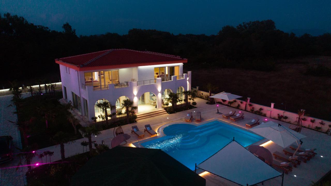 Stunning two-story white villa with red roof, balconies, pool, and lush ekosphere gardens&mdash;prime Ulcinj real estate by immobilien.ekosphere.me.