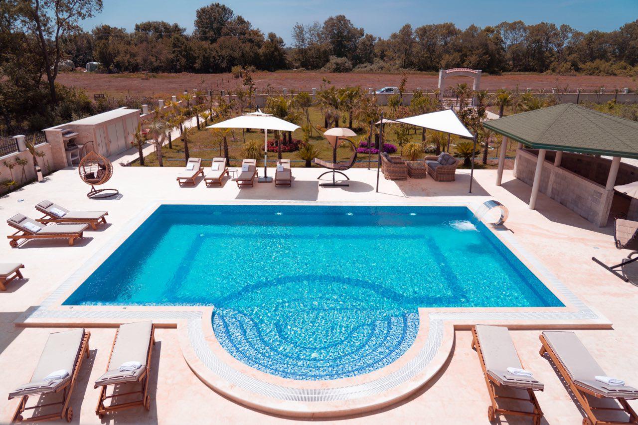 Luxurious pool with curved steps, lounge area, and scenic greenery&mdash;ideal Ulcinj property investment via immobilien.ekosphere.me by ekosphere doo.