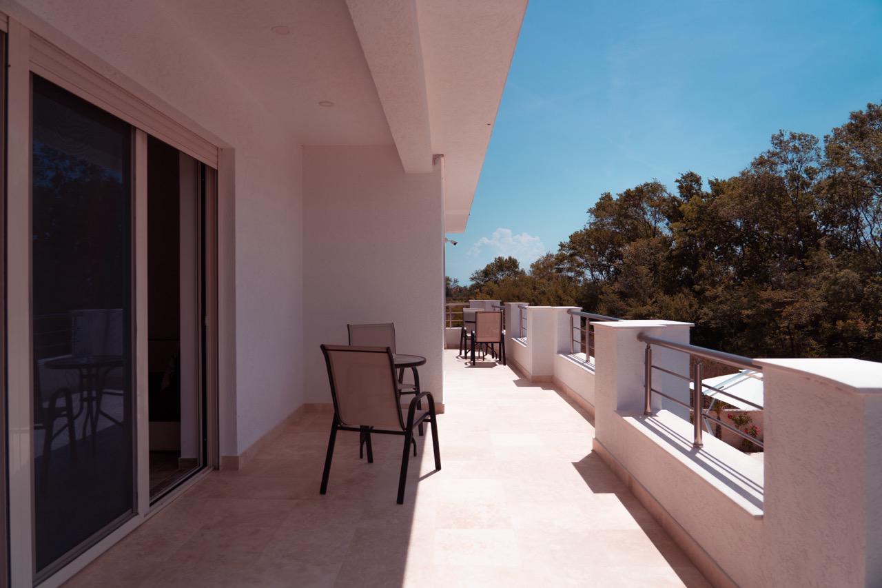 Modern Ulcinj balcony with light tiles, glass doors, stylish seating; prime real estate by ekosphere doo via immobilien.ekosphere.me.