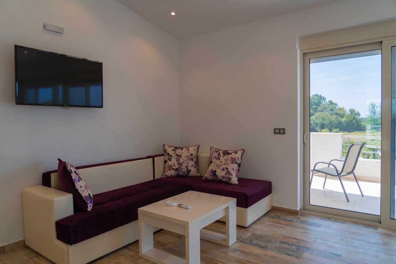 Stunning Ulcinj living room: elegant sofa, floral accents, balcony access&mdash;prime Montenegro investment from Ekosphere & immobilien.ekosphere.me.