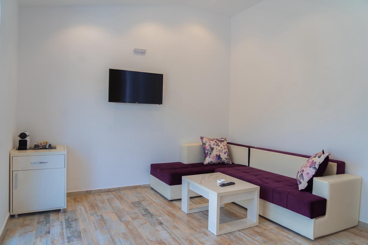 Contemporary Ulcinj Montenegro apartment: stylish sectional sofa, floral accents, sleek TV, wood floors&mdash;exclusive at immobilien.ekosphere.me by ekosphere doo.