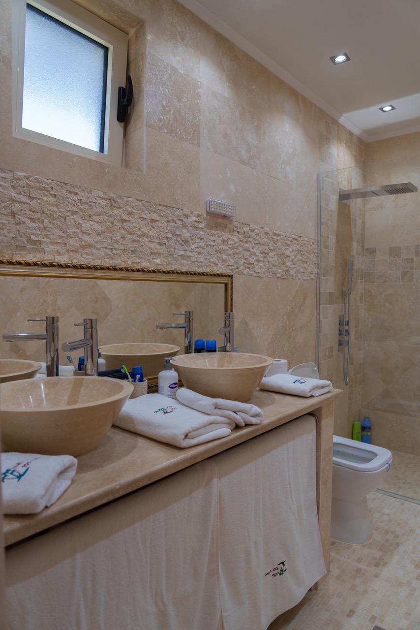 Elegant modern bathroom in Ulcinj real estate, tiled, dual vessel sinks, glass shower; exclusive on immobilien.ekosphere.me by ekosphere doo.