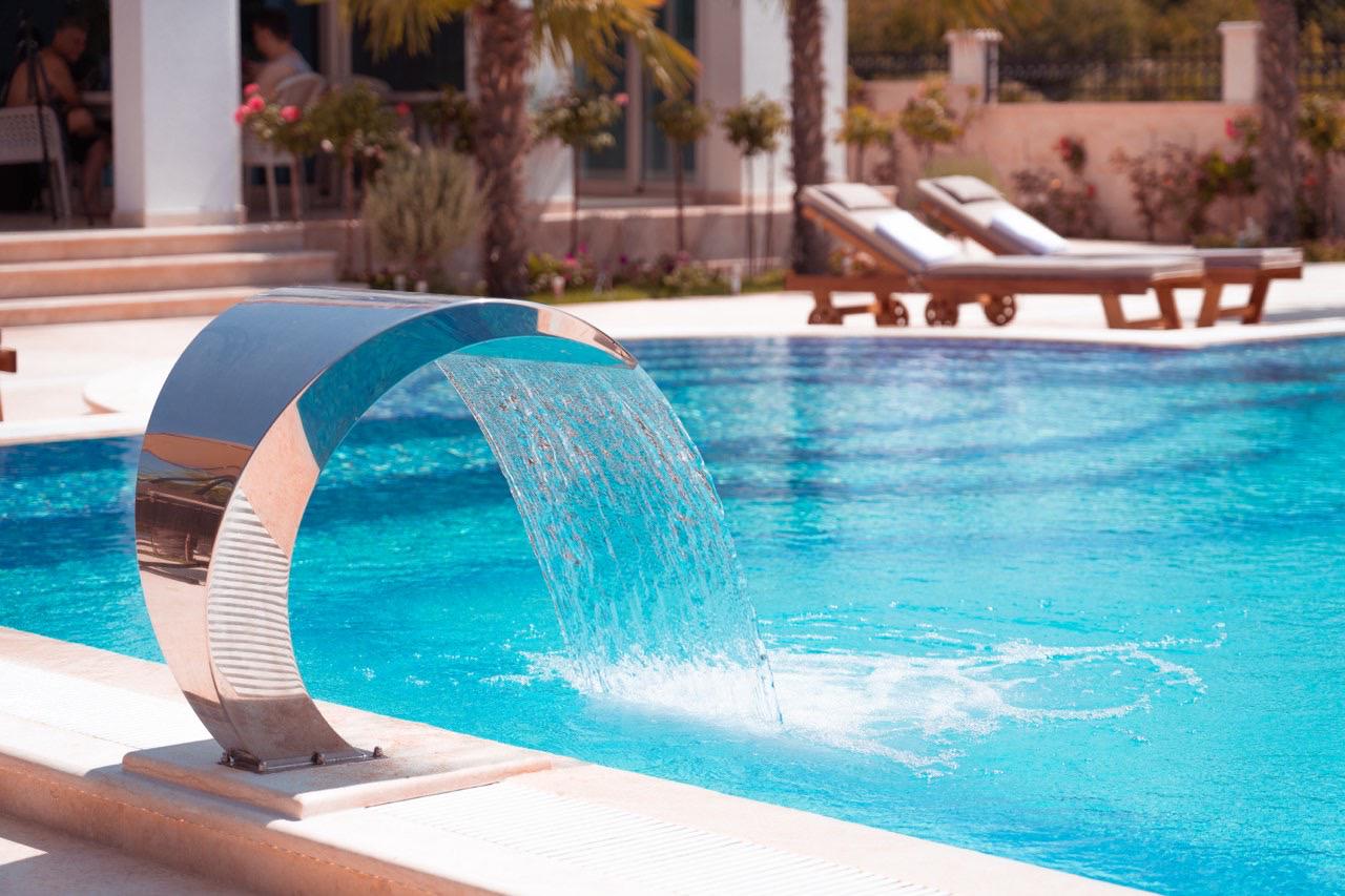 Luxury Ulcinj villa: sleek pool, waterfall feature, palm trees, stylish lounges&mdash;exclusive Montenegro real estate by Ekosphere | immobilien.ekosphere.me.