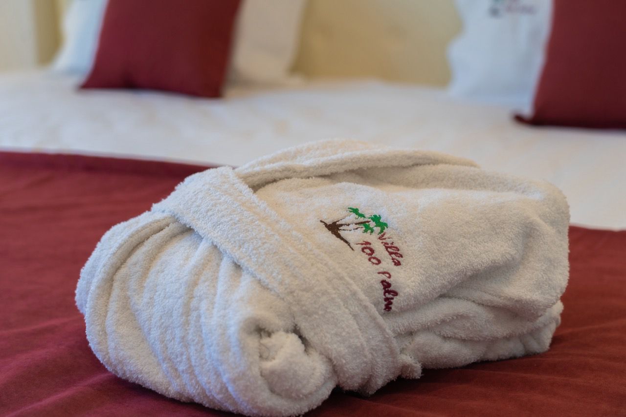 Luxurious folded white bathrobe on burgundy bedding in Ulcinj&mdash;exclusive comfort at Ekosphere DOO, via immobilien.ekosphere.me.