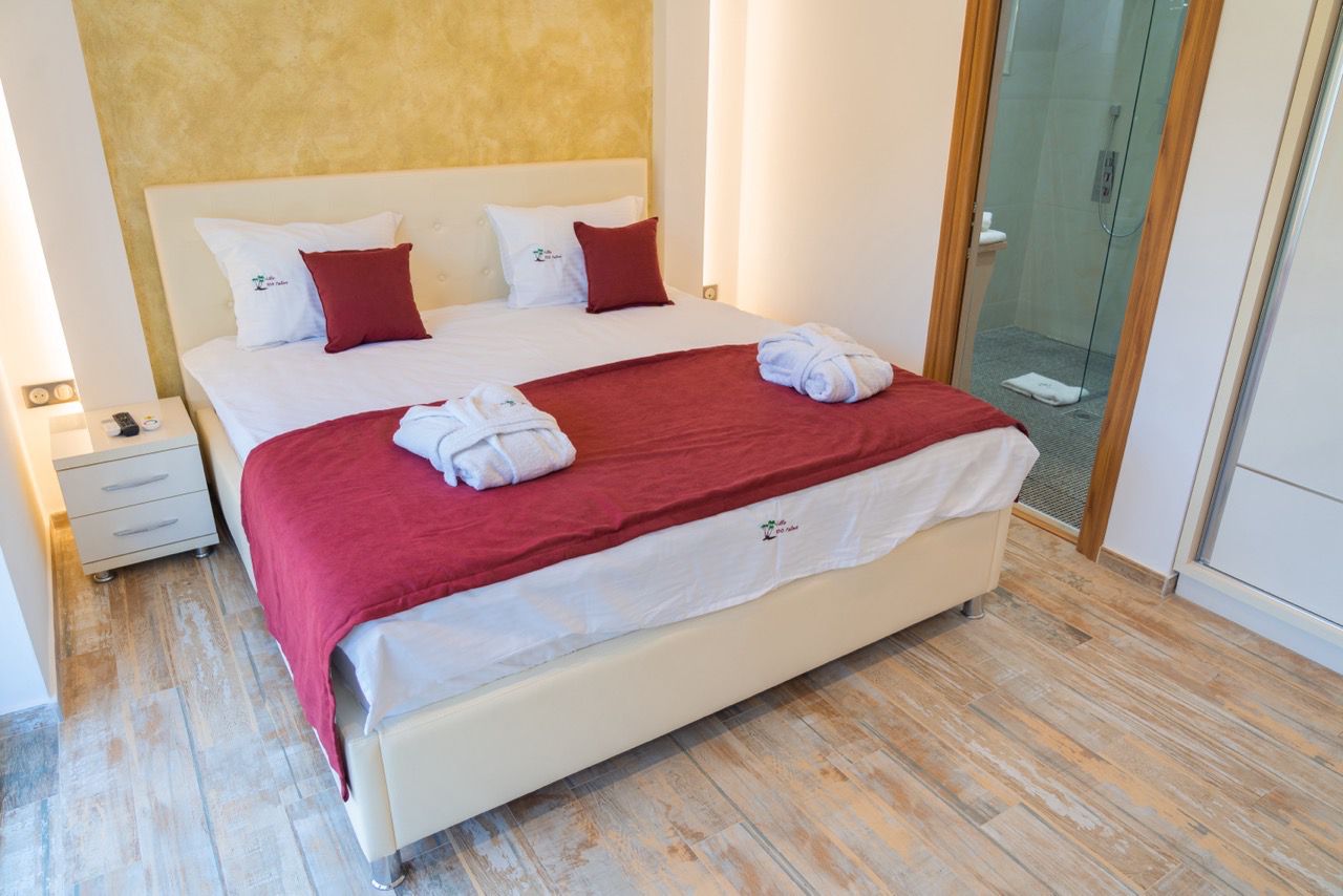 Modern Ulcinj bedroom with stylish red bedding, white headboard, ensuite bath&mdash;ideal investment via immobilien.ekosphere.me by ekosphere doo.