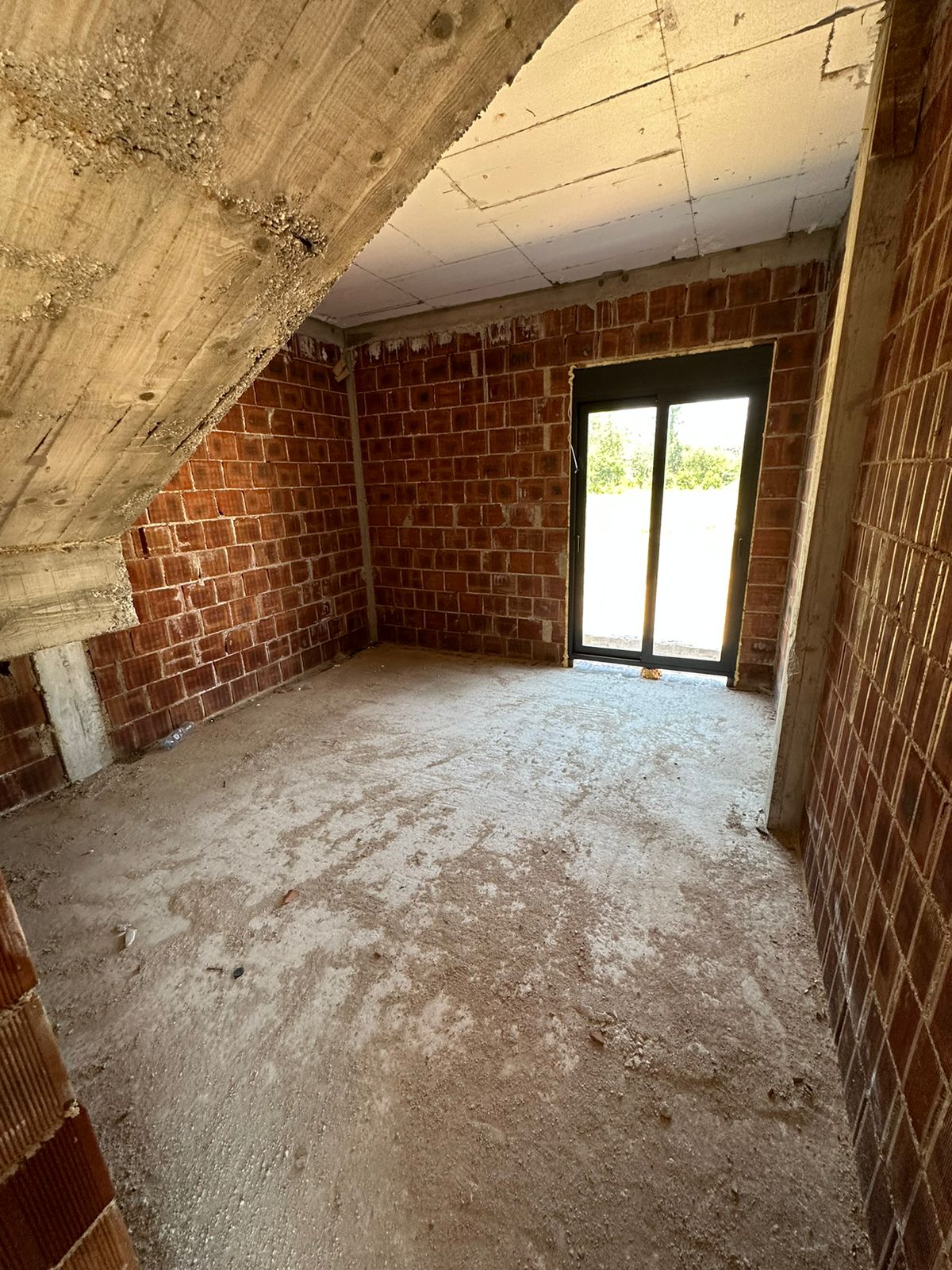 Spacious unfinished Ulcinj property with brick walls, concrete floor, and bright glass door&mdash;prime investment by ekosphere doo.