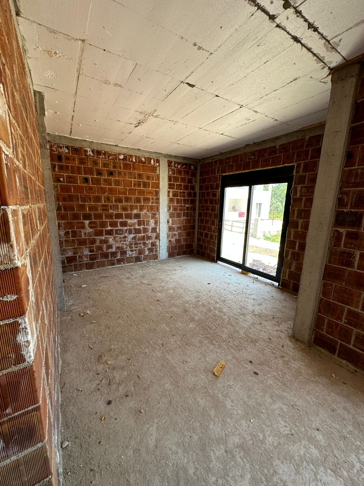 Spacious unfinished room in Ulcinj, Montenegro. Brick walls, concrete floor, sliding glass door. Exclusive on immobilien.ekosphere.me by Ekosphere DOO.