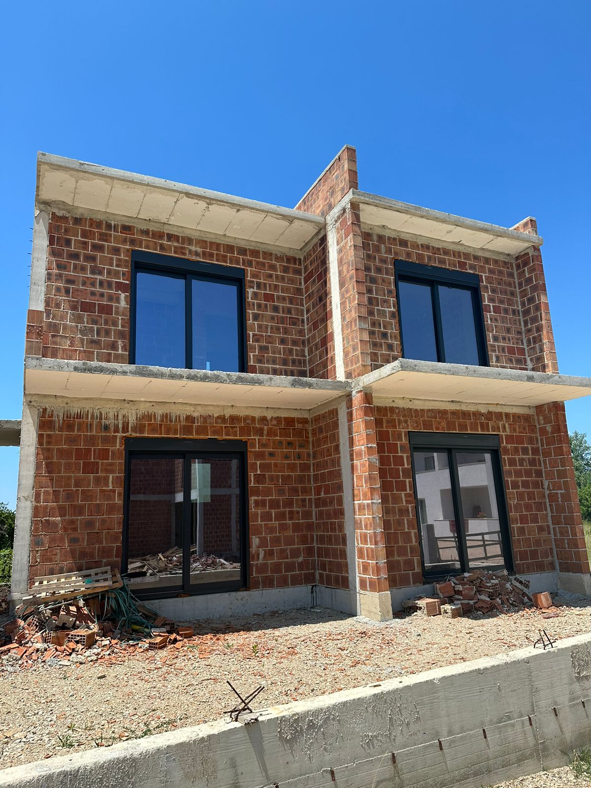 Modern two-story house under construction in Ulcinj, Montenegro&mdash;prime real estate with brick walls, large windows, and investment potential. Montenegro-listings.me by Ekosphere DOO.