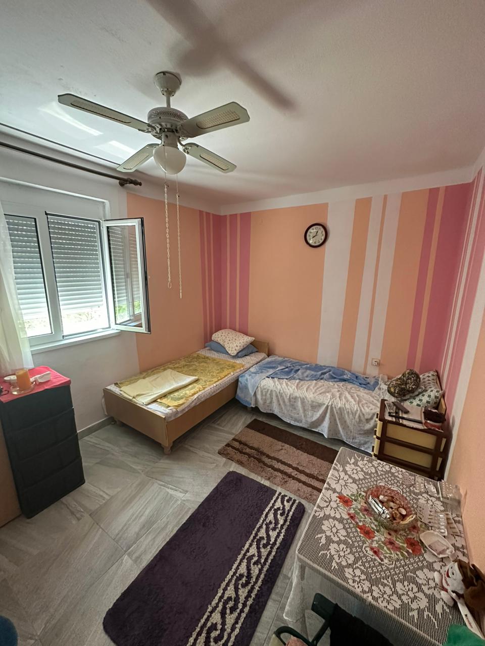Charming Ulcinj bedroom: 2 single beds, ceiling fan, bright window, ideal for investment. Listed on immobilien.ekosphere.me by Ekosphere DOO.