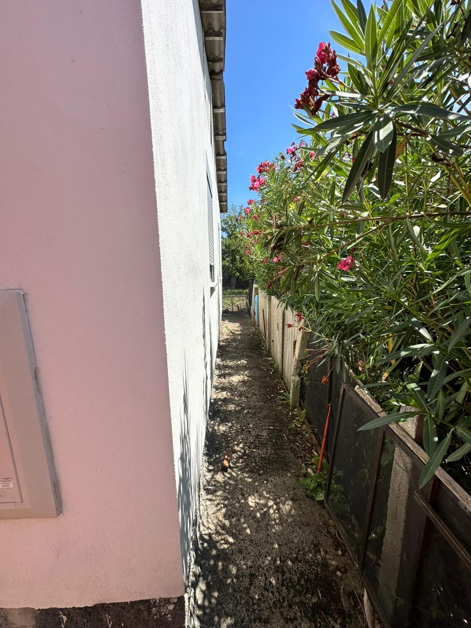 Charming walkway by a modern white building, lush gardens, and secure fencing&mdash;prime Ulcinj real estate via immobilien.ekosphere.me by ekosphere doo.