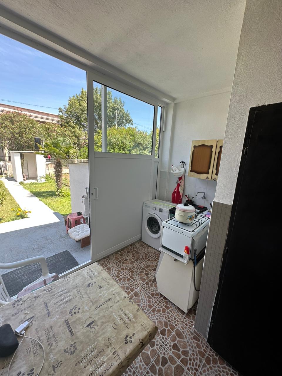 Modern Ulcinj laundry area with washer, stove, tiled floors, glass garden door&mdash;ideal eco-investment at immobilien.ekosphere.me by Ekosphere.