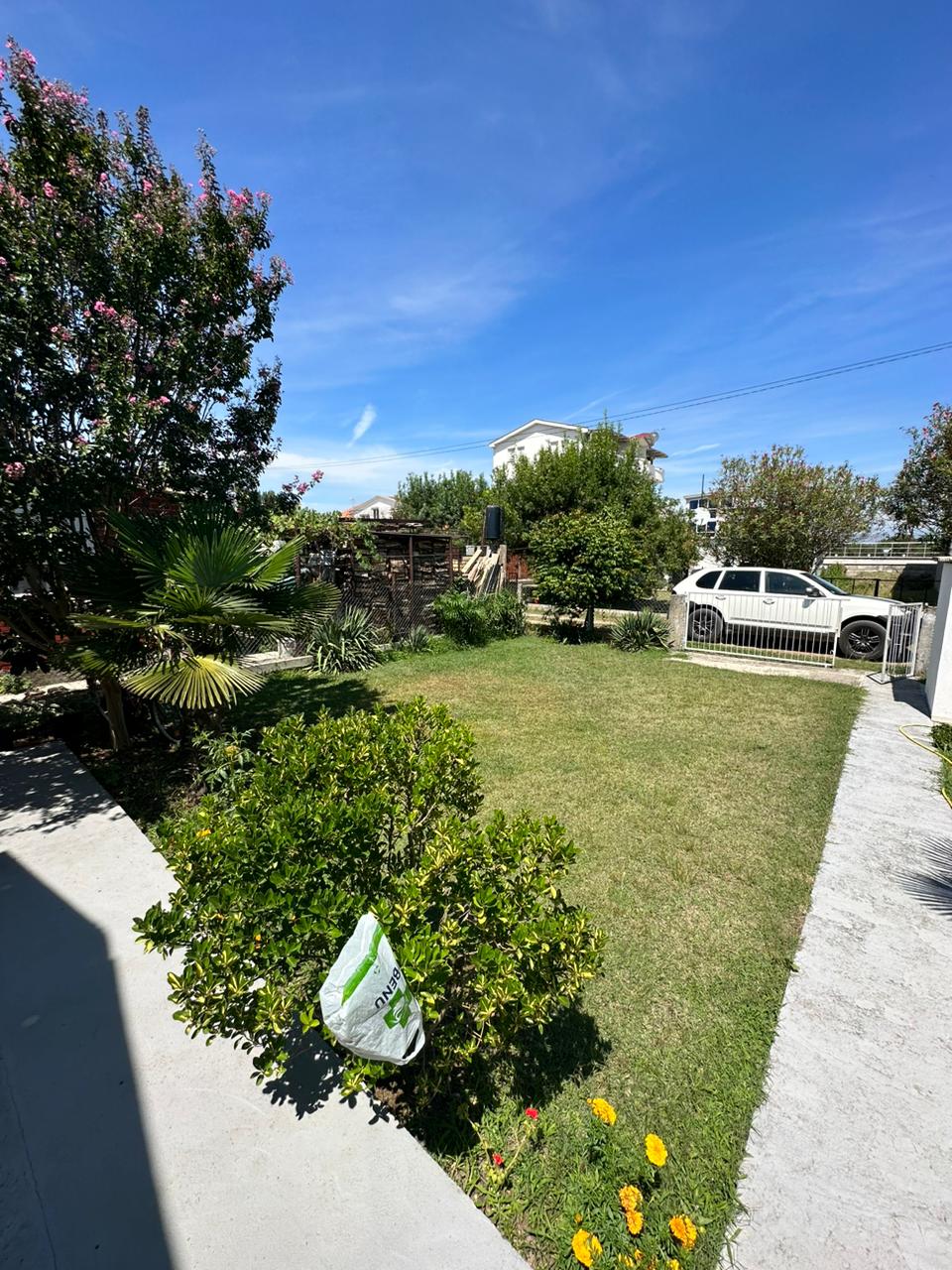 Discover this Ulcinj Montenegro property: lush lawn, mature trees, gated access, and prime curb appeal. Invest via immobilien.ekosphere.me by ekosphere doo.