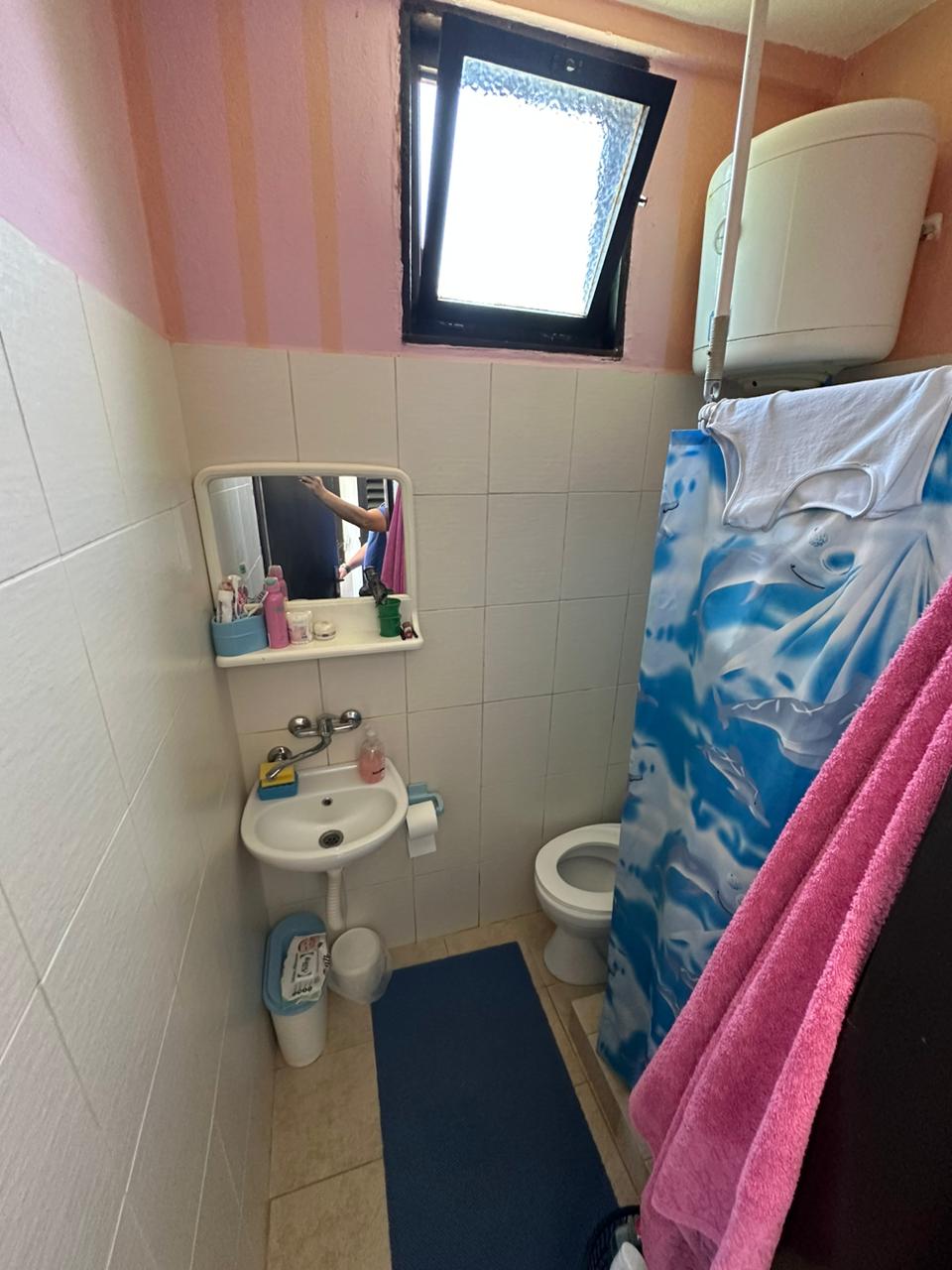 Bright bathroom in Ulcinj property: white tiles, sink with mirror, shower, window. Invest via immobilien.ekosphere.me by Ekosphere doo.