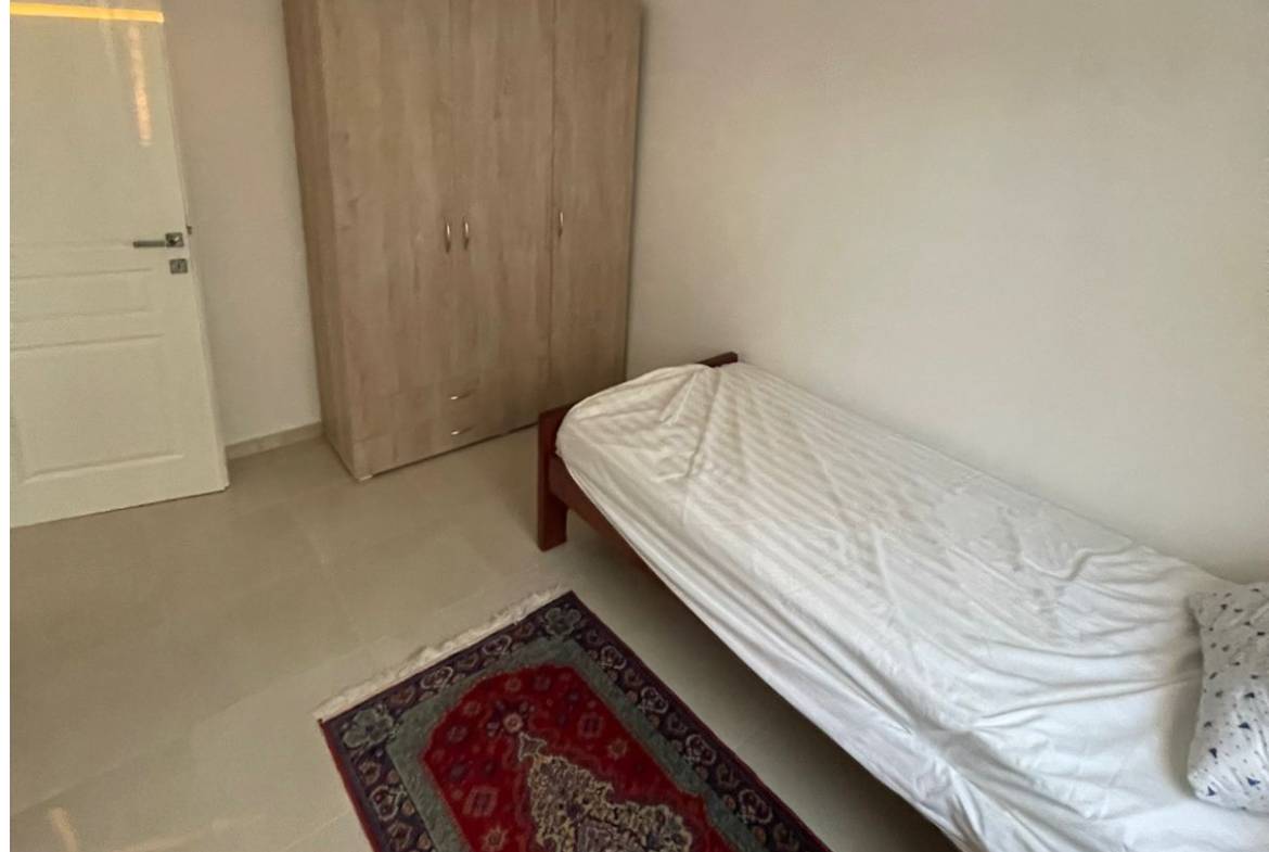 Modern, airy Ulcinj bedroom with white bed, wardrobe, and rug&mdash;ideal Montenegro property investment by Ekosphere on immobilien.ekosphere.me.