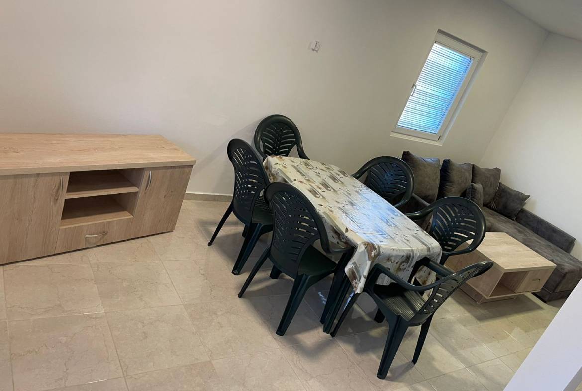 Modern Ulcinj property dining area with sleek table, six black chairs, sofa, and wood details&mdash;exclusive at immobilien.ekosphere.me.