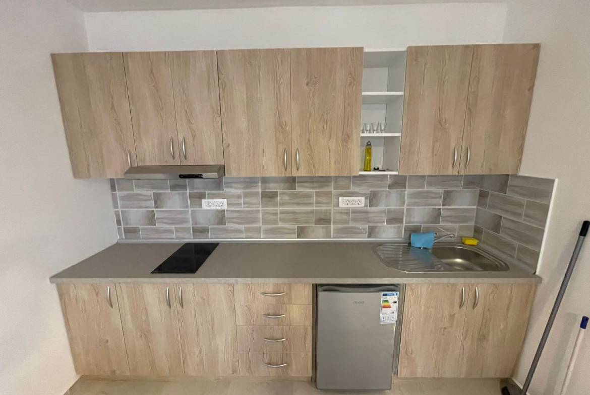 Modern Ulcinj kitchen with light wood cabinets, sleek backsplash, and cooktop&mdash;ideal property investment on immobilien.ekosphere.me by ekosphere doo.