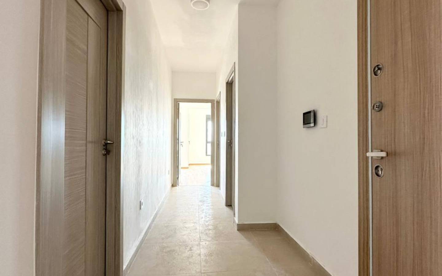 Spacious hallway in Ekosphere DOO Ulcinj property&mdash;beige tiles, white walls, wood doors; bright, investment-ready. Montenegro-listings.me.
