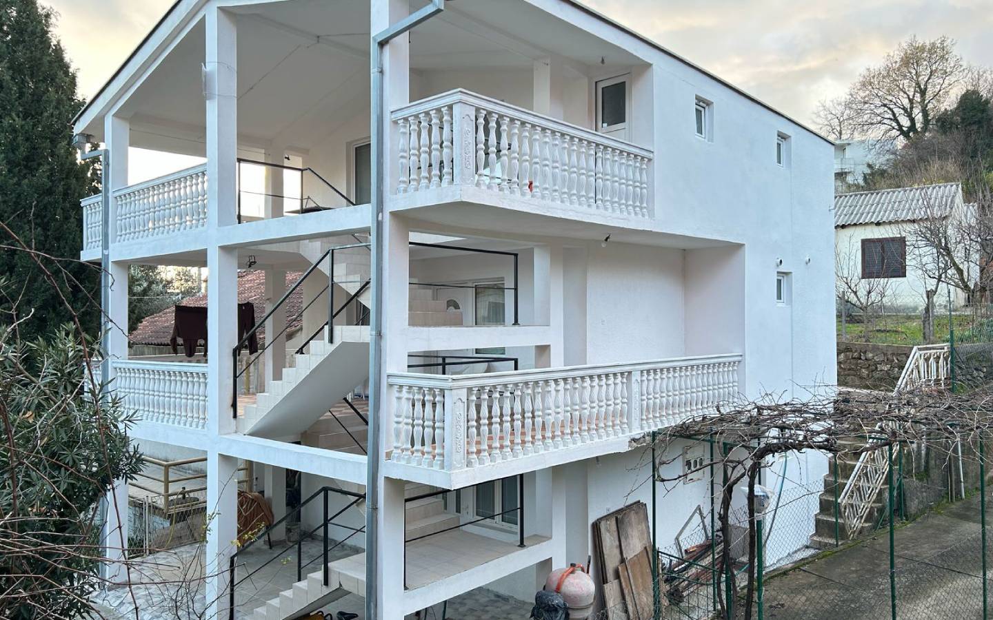 Modern three-story white home in Ulcinj, Montenegro with balconies and lush trees&mdash;exclusive listing on immobilien.ekosphere.me by ekosphere doo.