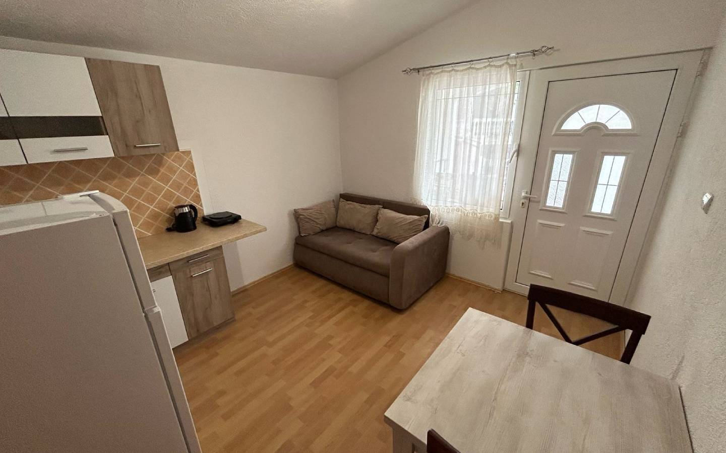 Modern Ulcinj studio with light wood floors, compact kitchen, and cozy furnishings&mdash;prime real estate via immobilien.ekosphere.me by ekosphere doo.