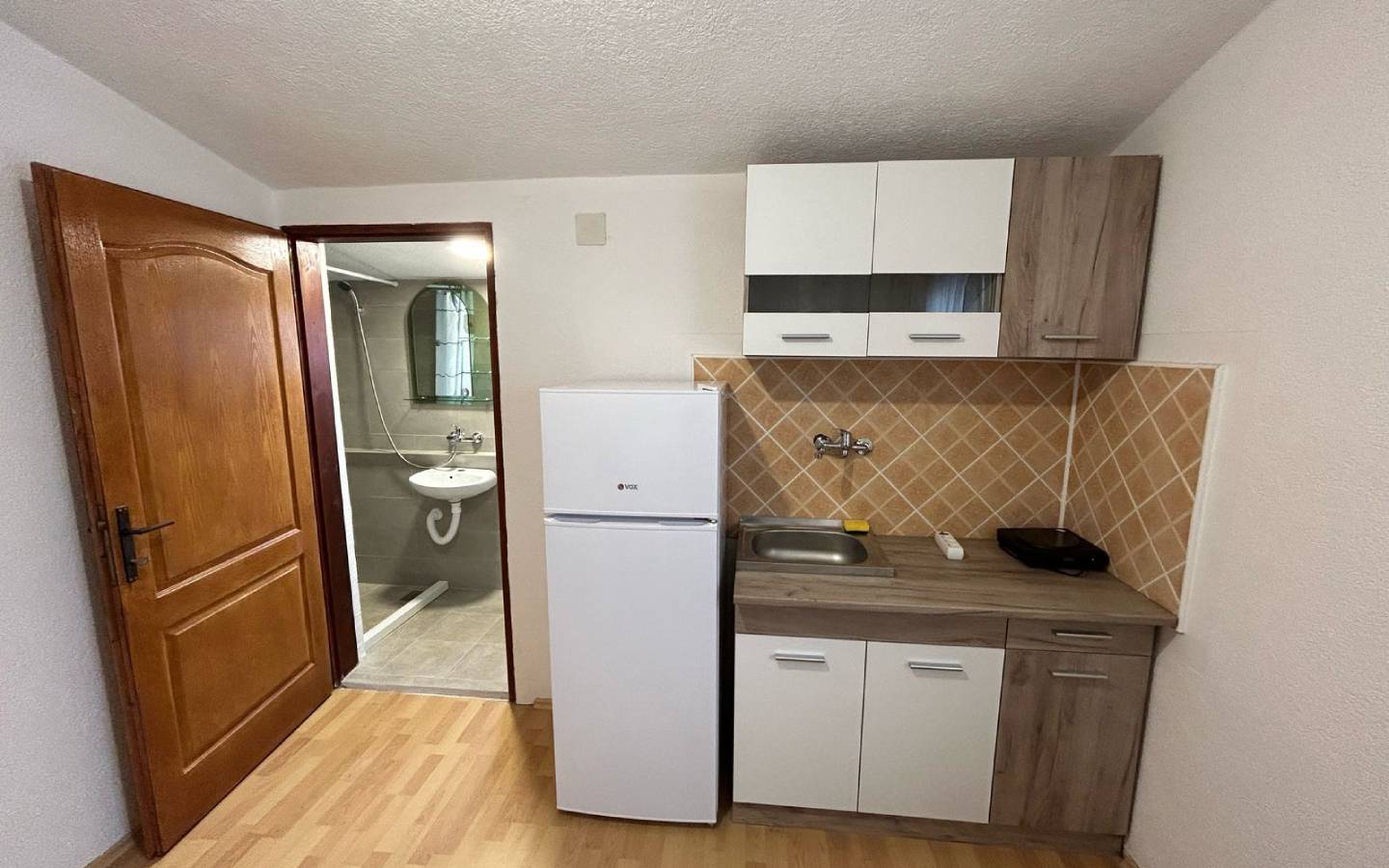 Modern compact kitchen in Ulcinj, Montenegro with appliances, stylish backsplash, and ensuite bath&mdash;exclusive at immobilien.ekosphere.me by Ekosphere.