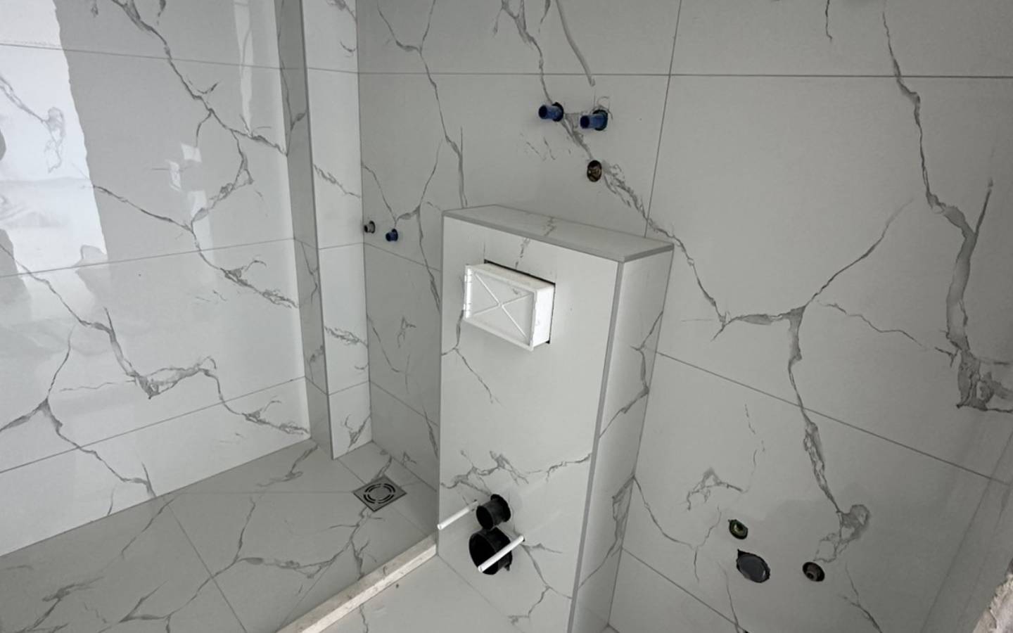 Badezimmer im Bau in Ulcinj mit eleganten Marmorfliesen, hochwertigen Armaturen - exklusive Immobilien von Ekosphere bei immobilien.ekosphere.me.