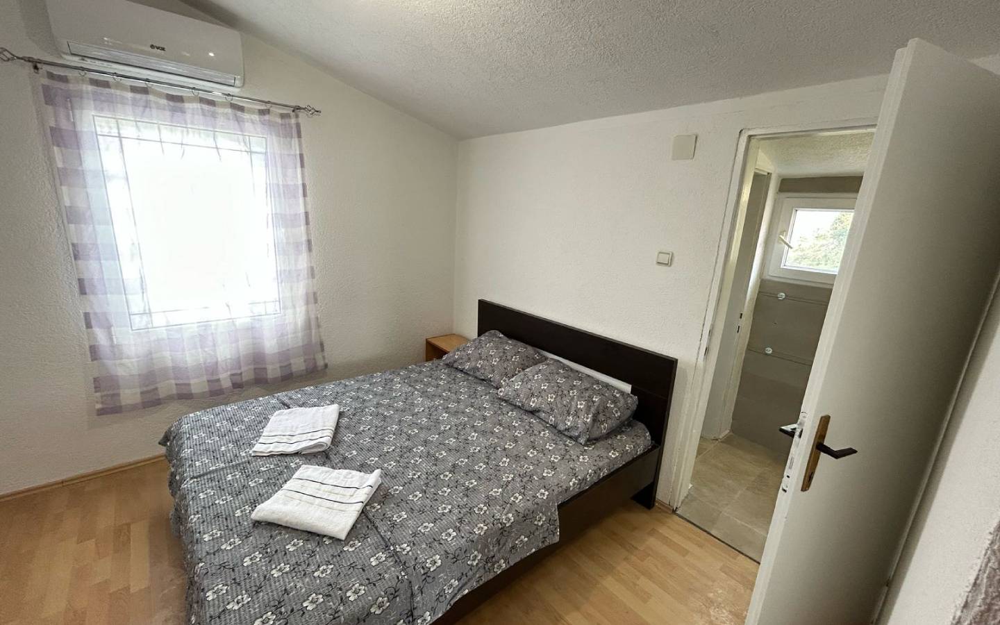 Modern Ulcinj bedroom with double bed, stylish wood floors, ensuite bath; top Montenegro investment on immobilien.ekosphere.me by Ekosphere.