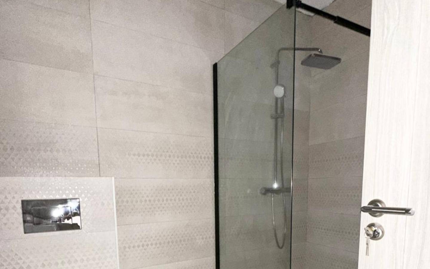 Sleek Ulcinj bathroom with light tiles, glass shower, rainfall head&mdash;prime Montenegro real estate by ekosphere doo on immobilien.ekosphere.me.