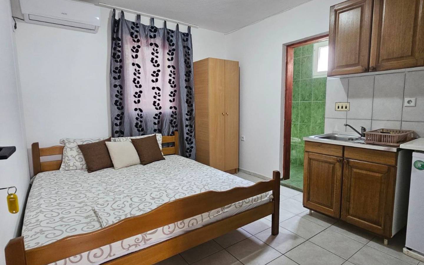 Modern Ulcinj studio: wooden bed, chic kitchenette, green-tiled bath. Smart eco-investment by Ekosphere on immobilien.ekosphere.me.