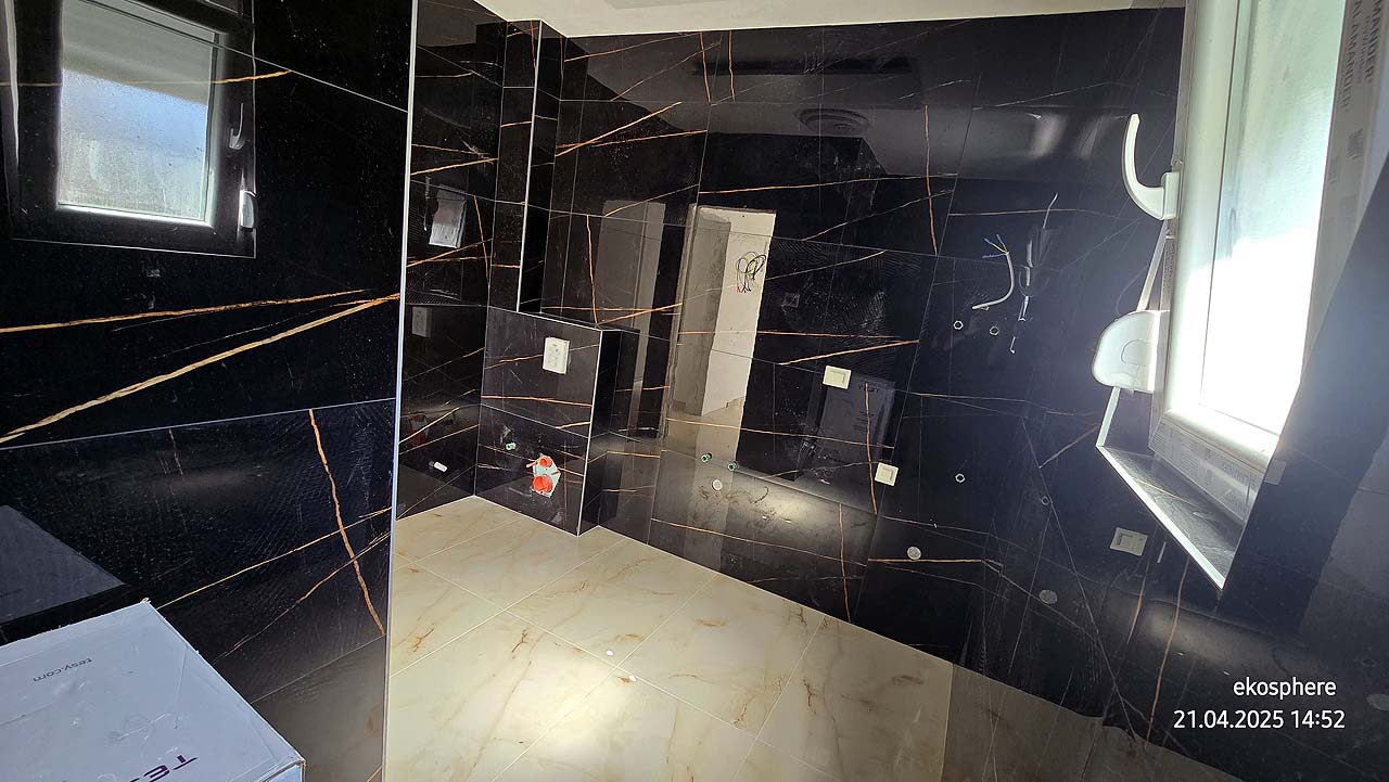 Modern bathroom in Ulcinj, Montenegro&mdash;black orange-streaked walls, beige tiles, sunlit window. Exclusive on immobilien.ekosphere.me by ekosphere doo.