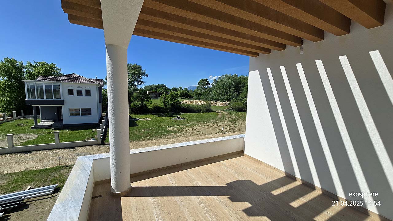 Bright covered balcony with wooden beams, lush yard, and modern home&mdash;prime Ulcinj real estate from immobilien.ekosphere.me/Ekosphere doo.