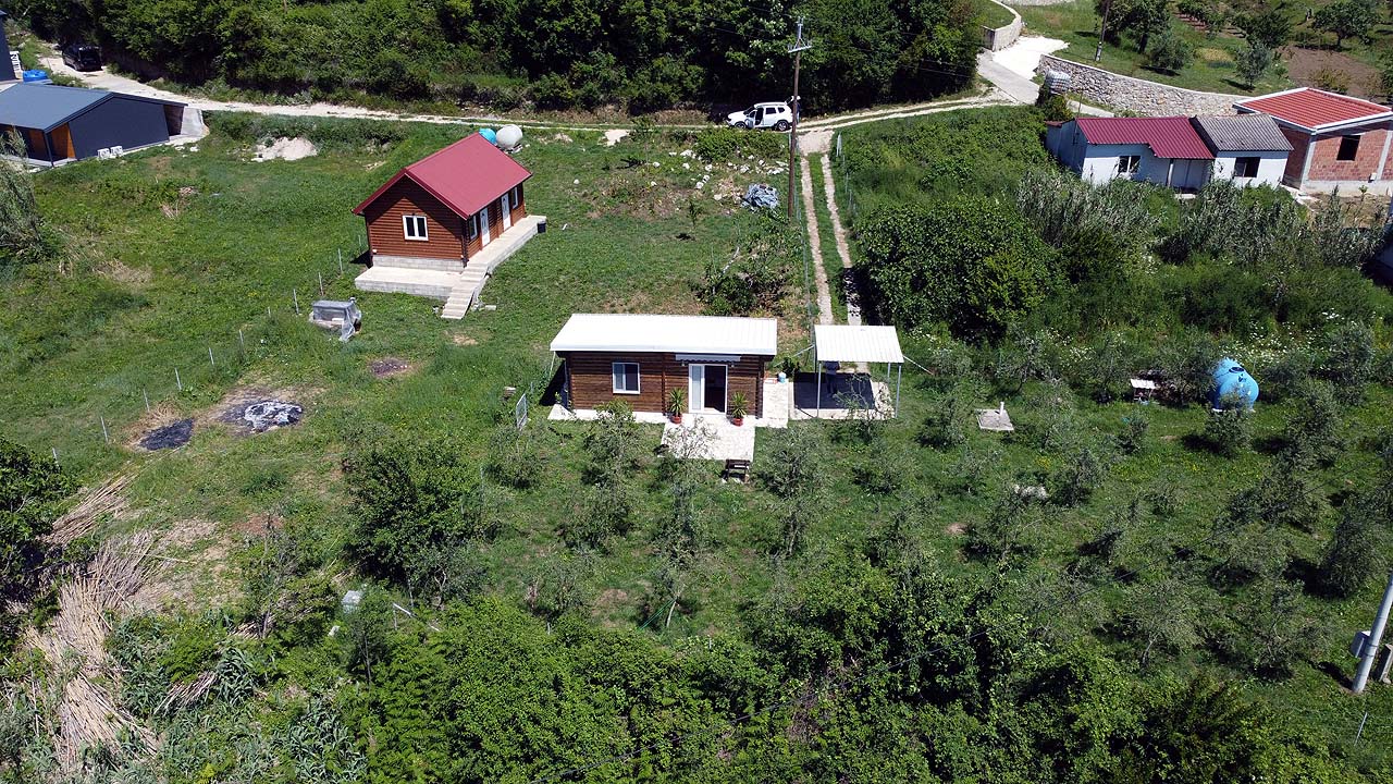 Luftaufnahme eines umweltfreundlichen Grundst&uuml;cks in Ulcinj: 2 Holzh&auml;user, Nebengeb&auml;ude, &uuml;ppiges Land. Investieren Sie &uuml;ber immobilien.ekosphere.me von Ekosphere doo. 