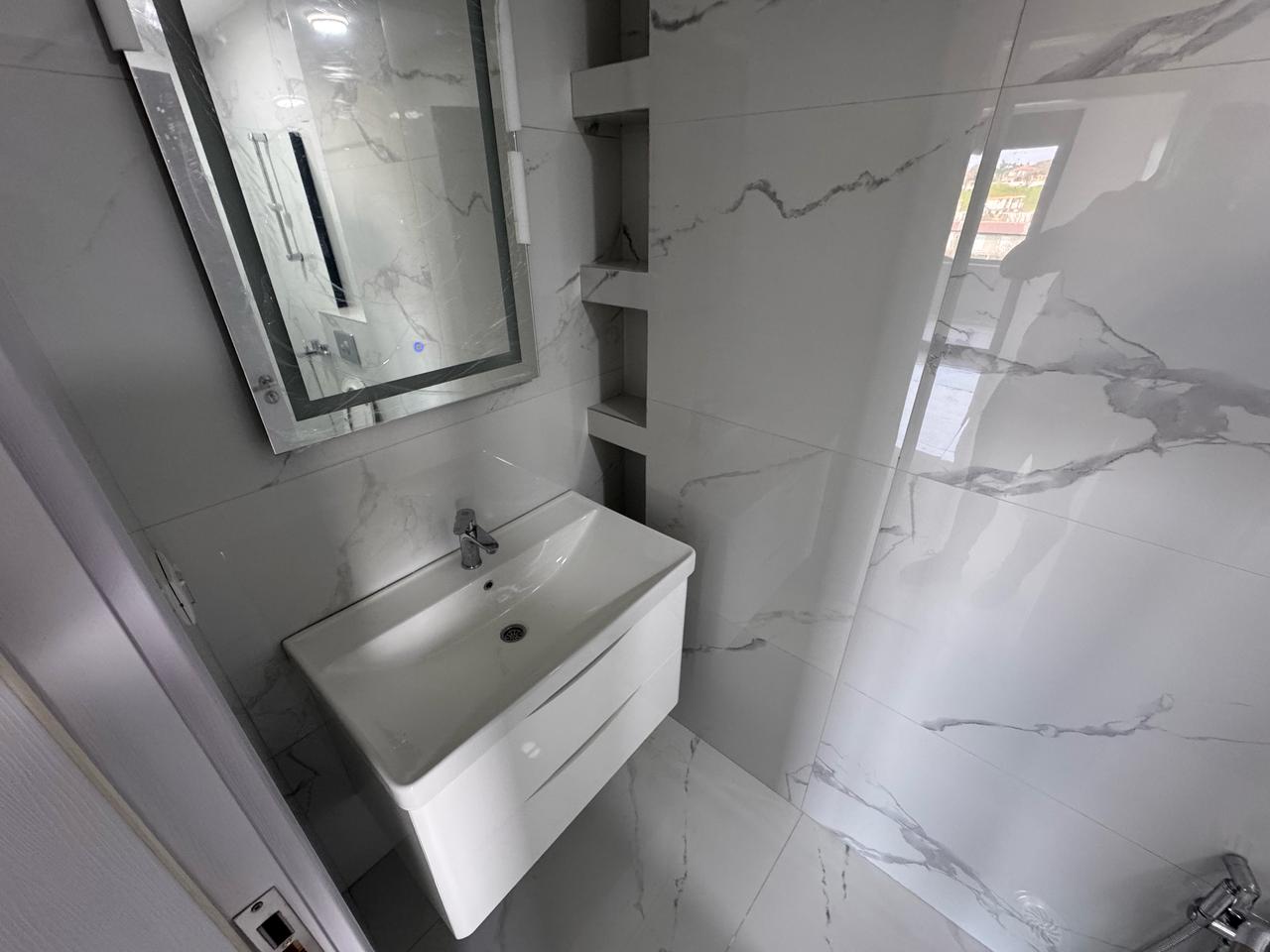 Luxury bathroom in Ulcinj: white marble, modern sink, built-ins, bright space. Invest with immobilien.ekosphere.me by Ekosphere D.O.O.