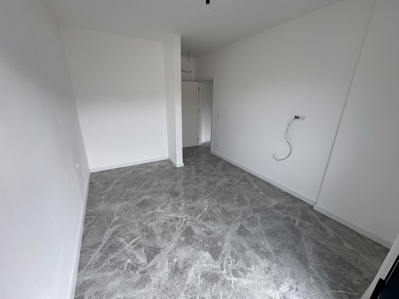 Spacious empty room in Ulcinj, Montenegro with white walls and gray tiled floor&mdash;prime investment from immobilien.ekosphere.me by Ekosphere.