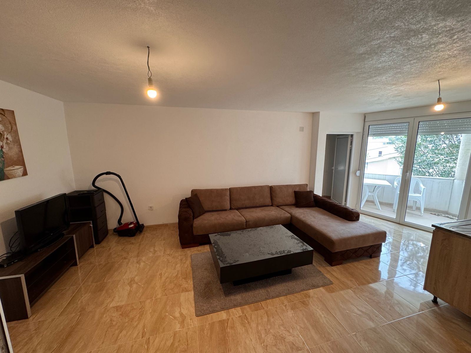 Elegant living room in prime Ulcinj property: brown sectional, modern amenities, balcony views. Exclusive on immobilien.ekosphere.me by ekosphere doo.