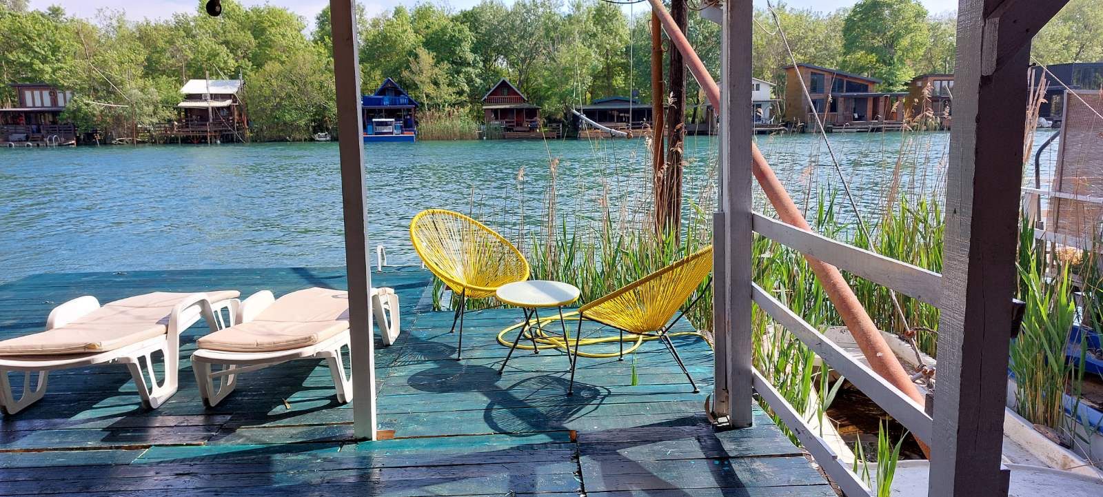 Stunning riverside deck in Ulcinj, Montenegro with yellow chairs and serene river views&mdash;exclusive on immobilien.ekosphere.me by Ekosphere doo.