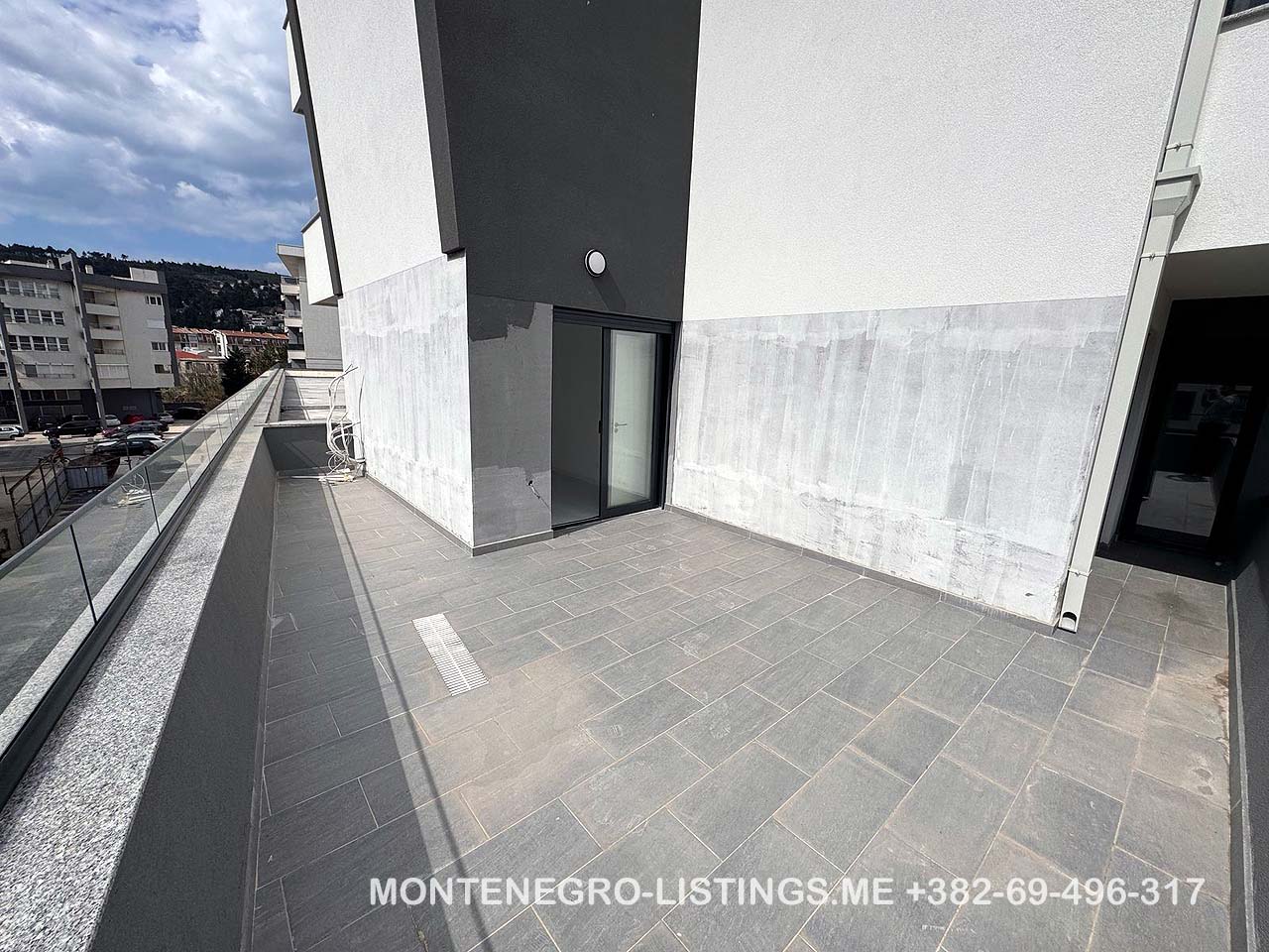 Moderne, unm&ouml;blierte Terrasse mit grauen Fliesen, Glasgel&auml;nder und Stadtblick in Ulcinj. Exklusives Angebot von ekosphere doo auf immobilien.ekosphere.me. 