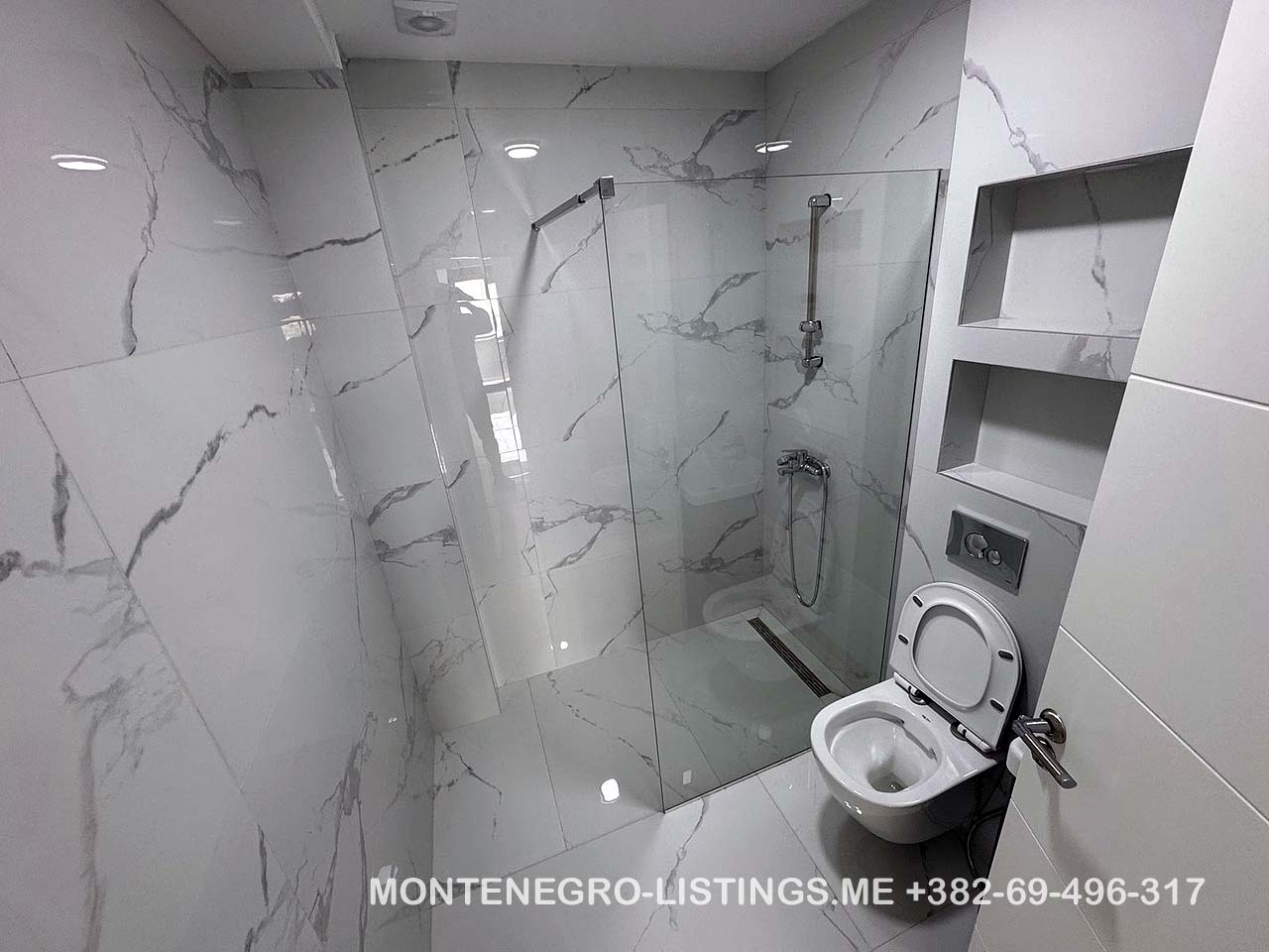 Luxurious Ulcinj bathroom with marble tiles, walk-in glass shower, and modern fixtures&mdash;exclusive at immobilien.ekosphere.me by Ekosphere doo.