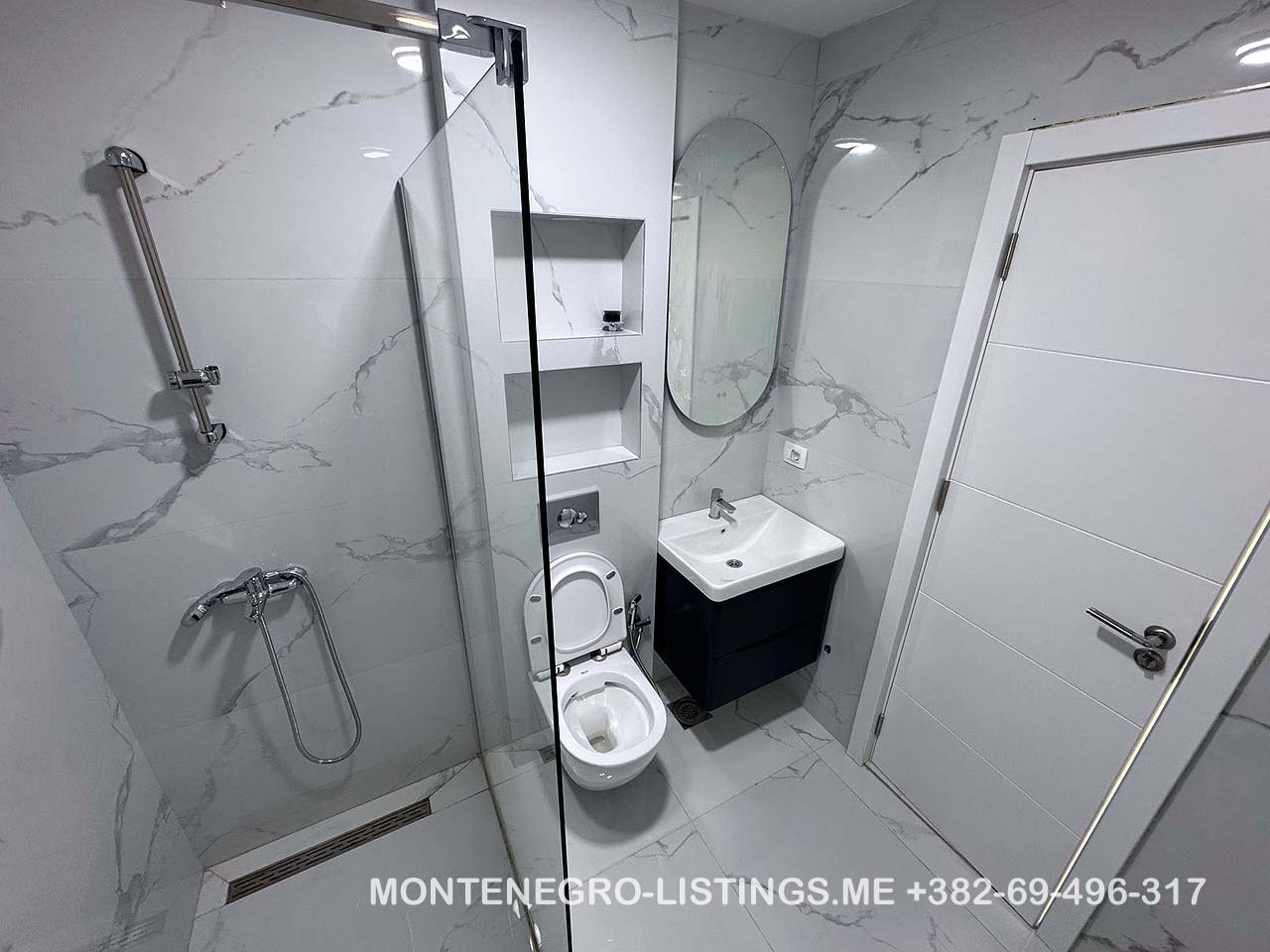 Elegant Ulcinj bathroom: marble tiles, glass shower, wall toilet, modern vanity&mdash;exclusive on immobilien.ekosphere.me by ekosphere doo.