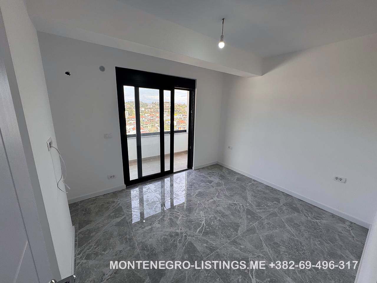 Spacious unfurnished room with tiled floors, balcony access, city and mountain views&mdash;ideal Ulcinj investment on immobilien.ekosphere.me.