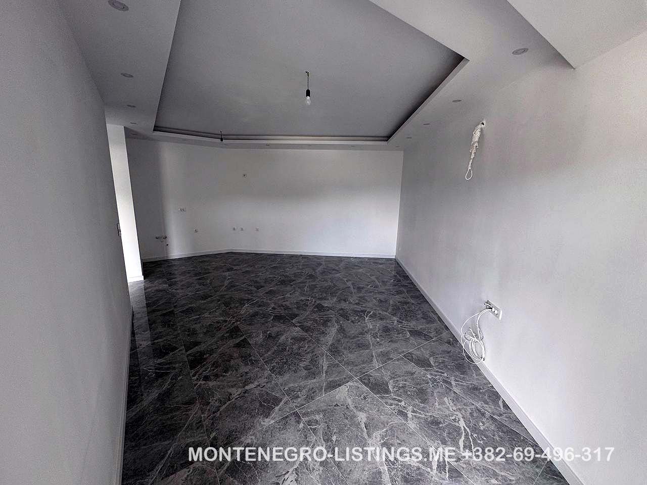 Spacious, modern room in Ulcinj with white walls, marble floors, and recessed lights&mdash;exclusive property at immobilien.ekosphere.me.